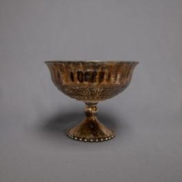 Bronze metallic pedestal compote bowl with decorative pattern on a gray background
