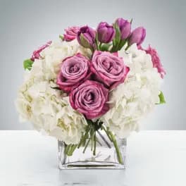 Pink roses and white flowers arranged in a clear square vase