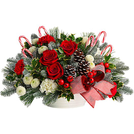 Christmas bouquet with red roses, carnations, pinecones, and candy canes in a white container