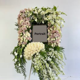 Large floral standing wreath on an easel with roses and white orchids around a portrait frame