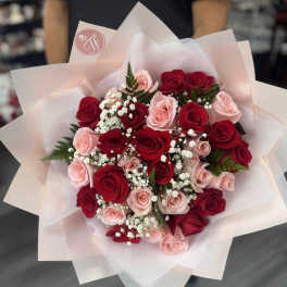 Bouquet of red and blush roses with white baby's breath in pale pink wrap