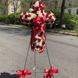 Standing floral cross of red roses and white flowers with red ribbon