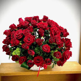 Large bouquet of red roses in a white basket with a red ribbon