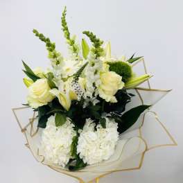 Bouquet of white and pale yellow flowers wrapped in clear paper with gold trim