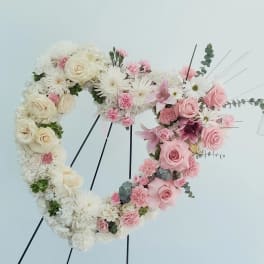 Heart-shaped floral wreath with white and pink flowers on a stand