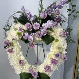 Heart-shaped floral wreath with lavender roses and white blooms on an easel