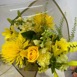Yellow bouquet with lilies, roses, and chrysanthemums wrapped in clear paper