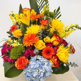 Bright mixed bouquet with roses, gerberas, lilies, and blue hydrangea in a vase