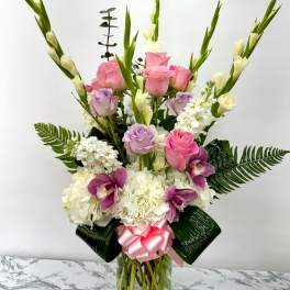 Pink and lavender roses with white flowers in a glass vase
