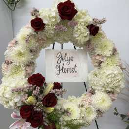 Large floral wreath with white blooms and red roses on an easel