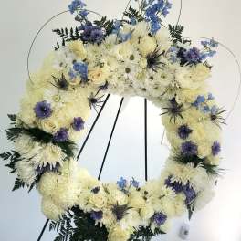 Large floral wreath of white and blue flowers on a black stand