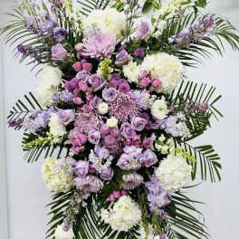 Large standing floral spray in lavender, pink, and white on a stand