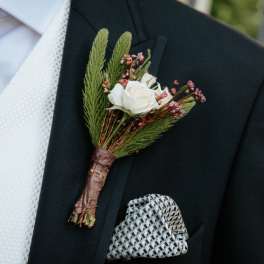 White rose boutonniere with pink filler on a suit jacket
