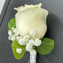 White rose boutonniere with baby's breath and green leaves