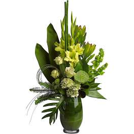 Tall green floral arrangement in a glass vase with lilies, roses, and tropical leaves