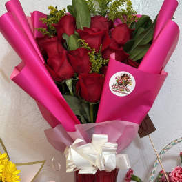 Bouquet of red roses wrapped in bright pink paper with a white bow