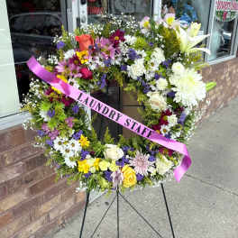Large floral wreath on a stand with a pink ribbon reading "LAUNDRY STAFF"