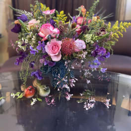 Mixed bouquet of pink, purple, and yellow flowers in a blue vase