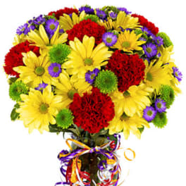 Bright bouquet of yellow daisies, red carnations, and green button mums in a glass vase