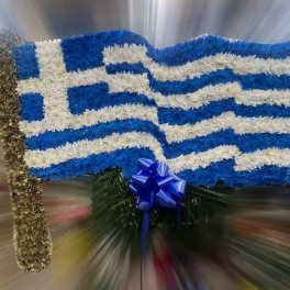 Floral arrangement shaped like the Greek flag with blue and white flowers and a blue ribbon bow