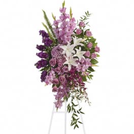 Tall lavender and white standing spray with lilies and roses on a white easel