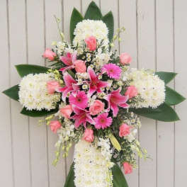 Standing cross-shaped funeral spray of white mums with pink lilies, roses, and gerbera daisies.