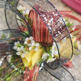 Yellow rose with small white blossoms and black and red ribbon loops