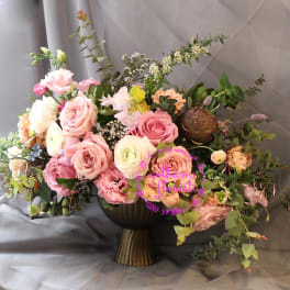 Large pastel bouquet of roses and mixed blooms in a dark vase