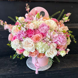 Pink and white mixed flower arrangement in a round pink box
