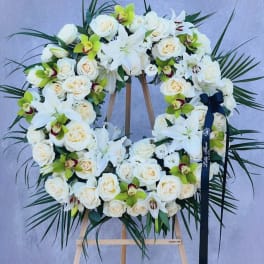 White floral wreath on a wooden easel with roses and orchids