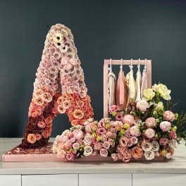 Pink rose floral display with a hanging rack of pastel clothes and a bouquet arrangement