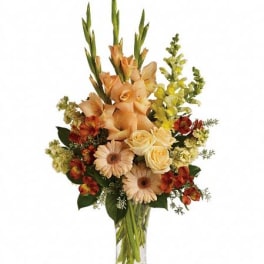 Tall peach and yellow mixed flower arrangement with roses and gerbera daisies in a clear glass vase