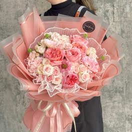 Large pink bouquet of roses and daisies wrapped in pink paper