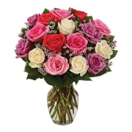 Mixed bouquet of red, pink, lavender, and cream roses in a clear glass vase