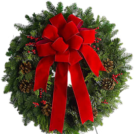 Christmas wreath with a large red bow on a metal stand