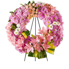 Pink floral wreath on a black easel with lilies and daisies