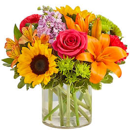Mixed bouquet with sunflowers, roses, lilies, and chrysanthemums in a glass vase