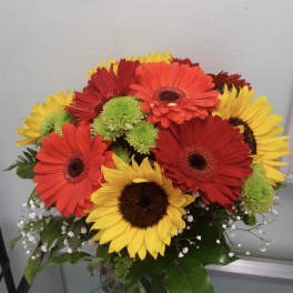 Bouquet of red, orange, and yellow gerbera daisies in a glass vase