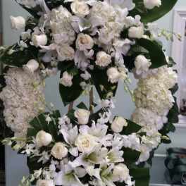 Large white floral standing spray with lilies, roses, and hydrangeas