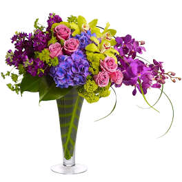Colorful bouquet of roses, hydrangeas, and orchids in a tall glass vase