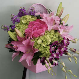 Pink roses and lilies with purple orchids in a pink heart-shaped box