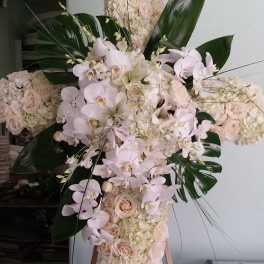 Large floral cross with pale roses and white orchids on an easel