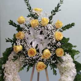 Yellow roses and white lilies in a standing floral wreath
