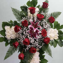 Standing floral cross with red roses, white flowers, and pink lilies