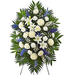 White and blue funeral spray with lilies and roses on a standing easel