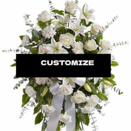 White floral standing spray with lilies and roses on a ribboned easel