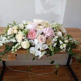 Low pastel floral arrangement with roses, peonies, and orchids on a table
