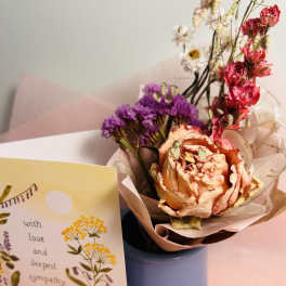 Bouquet of dried flowers in a blue vase beside a sympathy card
