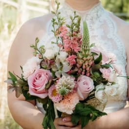 Bride holding a pink and white bouquet with roses and mixed blooms