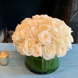 Round bouquet of white roses in a green glass vase